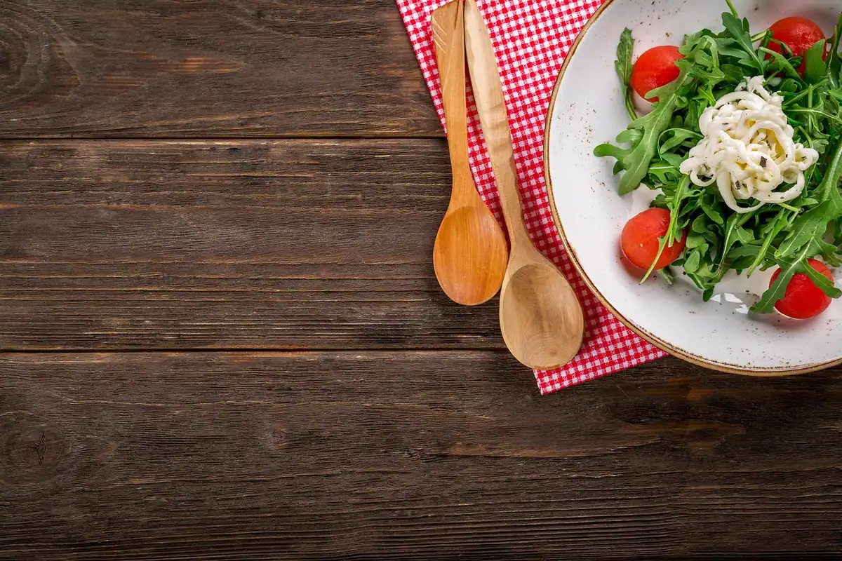 Farfurie cu salată de rucola și roșii cherry pe o masă de lemn