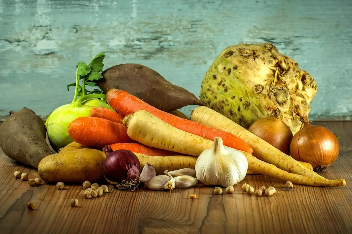 Morcovi, păstârnac, țelină și usturoi pe o masă de lemn, legume pentru o ciorbă ușoară