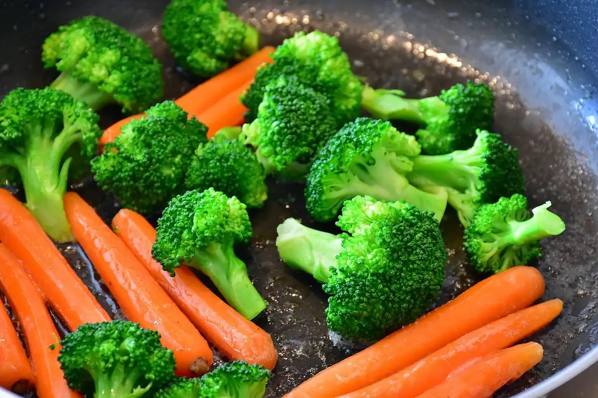 Broccoli și morcovi proaspeți în tigaie, legume potrivite pentru gătitul la abur