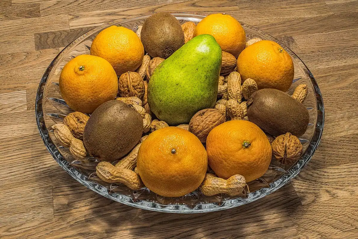 Bol de sticlă cu portocale, kiwi, pere și alune, gustări pentru drum