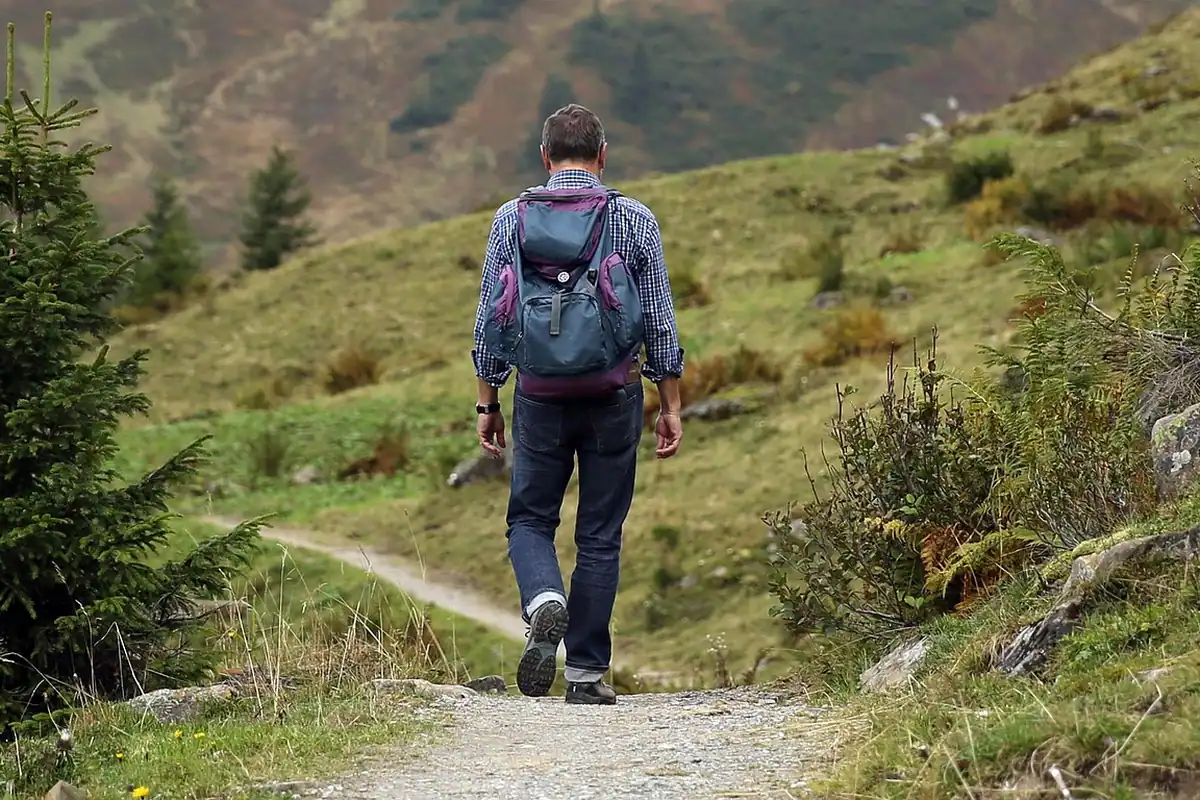Excursionist cu rucsac pe o potecă de munte, cu gustări luate la drum