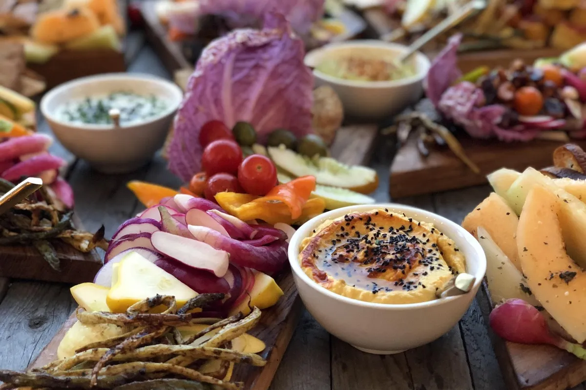 Platou cu hummus, legume crude tăiate și ierburi, pregătit pentru a înmuia în dip