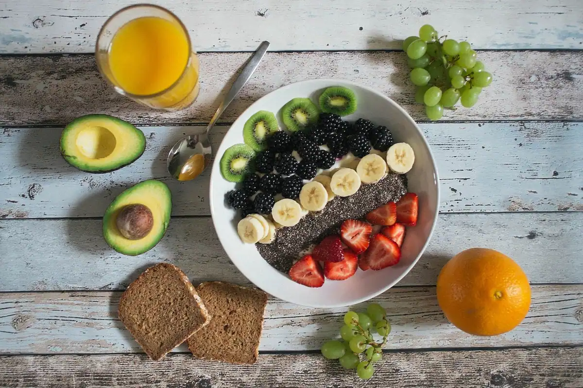 Bol cu fructe, fructe de pădure și semințe, lângă avocado și pâine, mâncat conștient