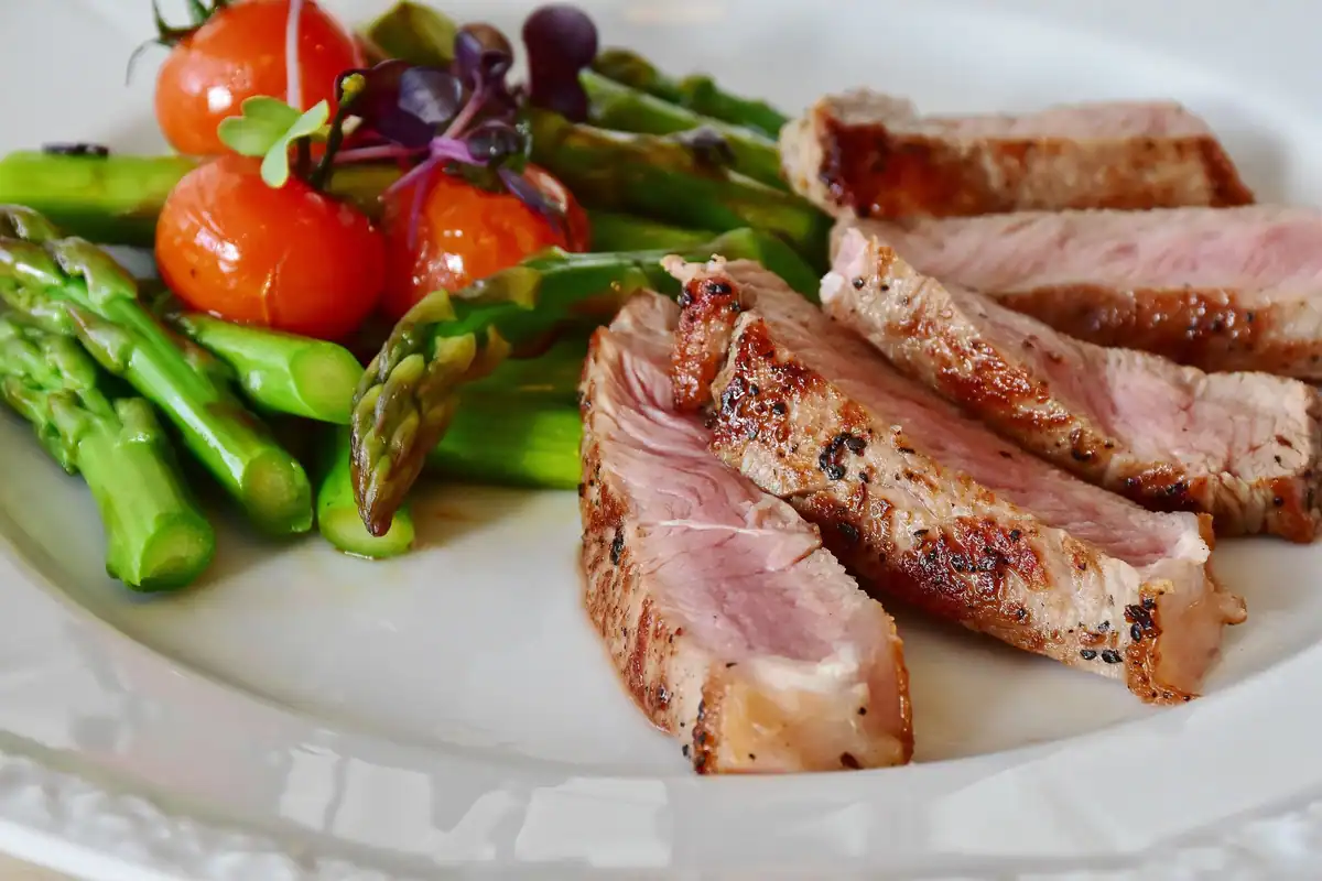 Farfurie cu felii de carne la grătar, sparanghel și roșii cherry, porții bine împărțite