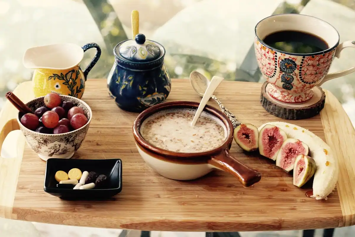 Masă de dimineață cu terci, struguri, smochine și cafea, într-un decor rustic